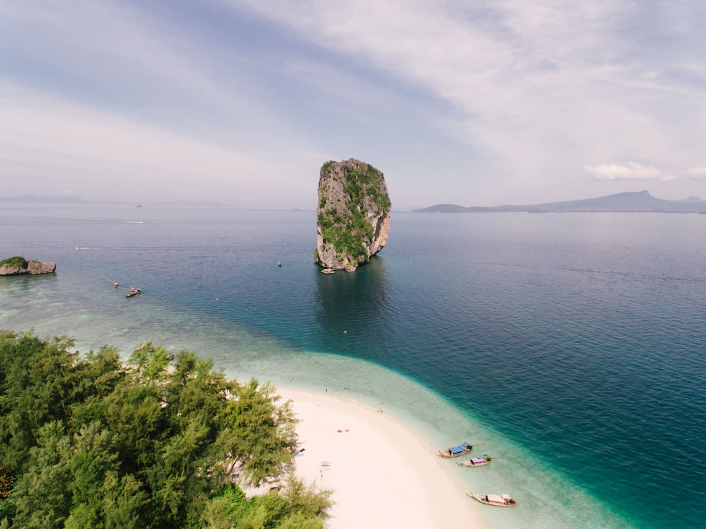 Limestone island rising from turquoise water off a tropical coastline