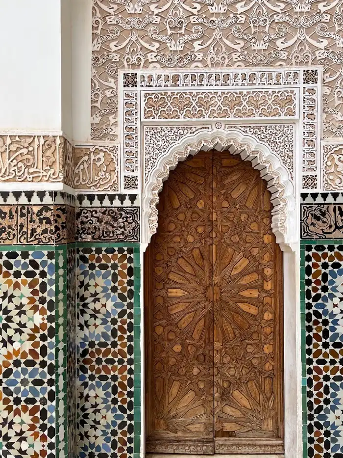 A carved wooden door framed by zellij tilework in the Marrakesh medina, Morocco