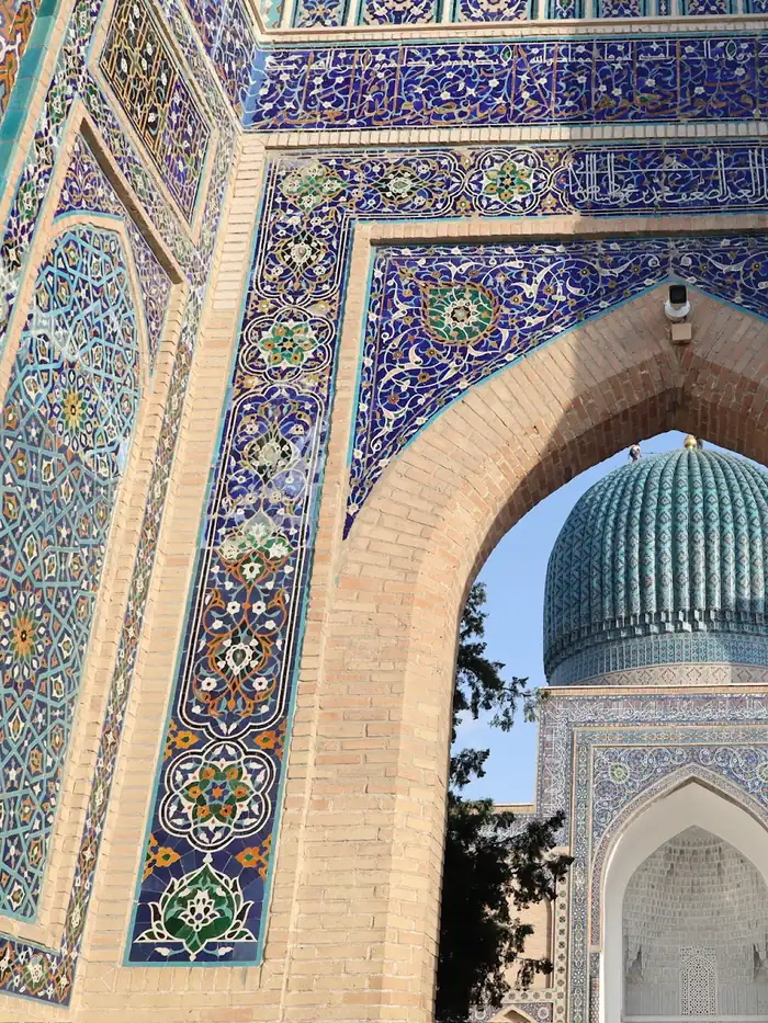 A tiled iwan portal framing a turquoise dome in Samarkand, Uzbekistan